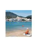 Woman sitting on a towel by the beach of Cadaqués.